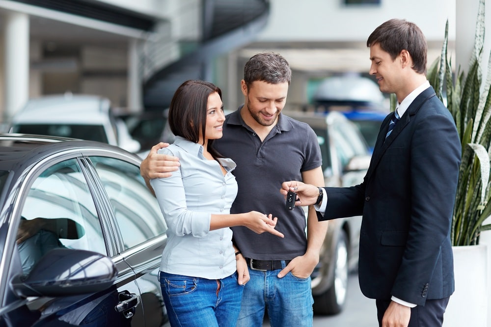 Couple receiving the car key in car rental services.