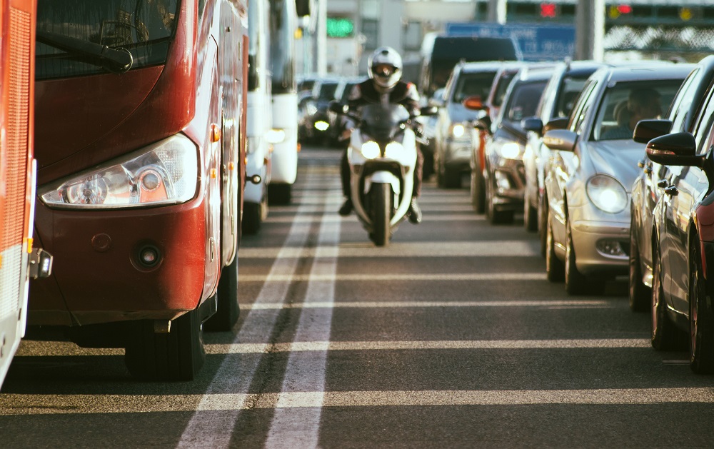 Motorcycle passing through lane splitting despite traffic.