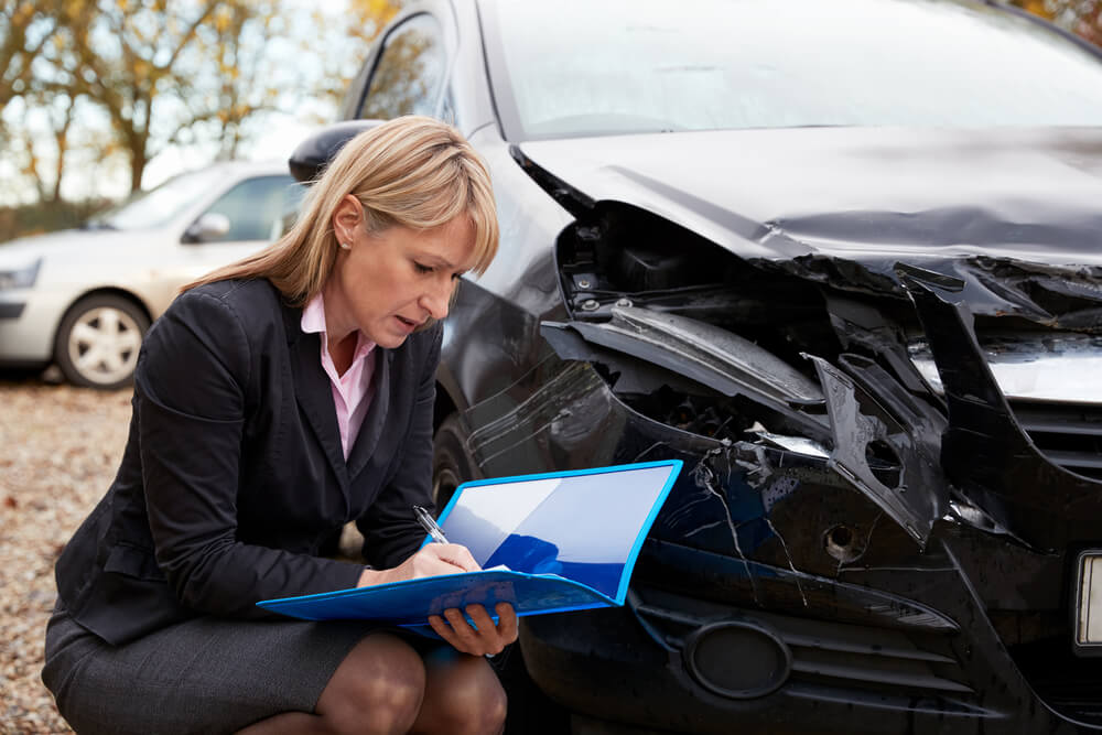 Insurance adjuster checking on damaged cars.